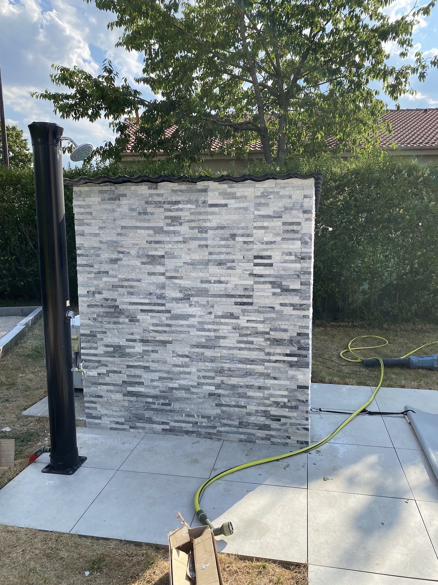 Douche de jardin : mur en plaquettes de pierre et dalles au sol